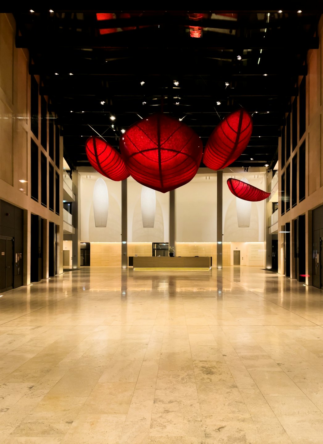 Modern corporate lobby with large red sculptural ceiling lights.