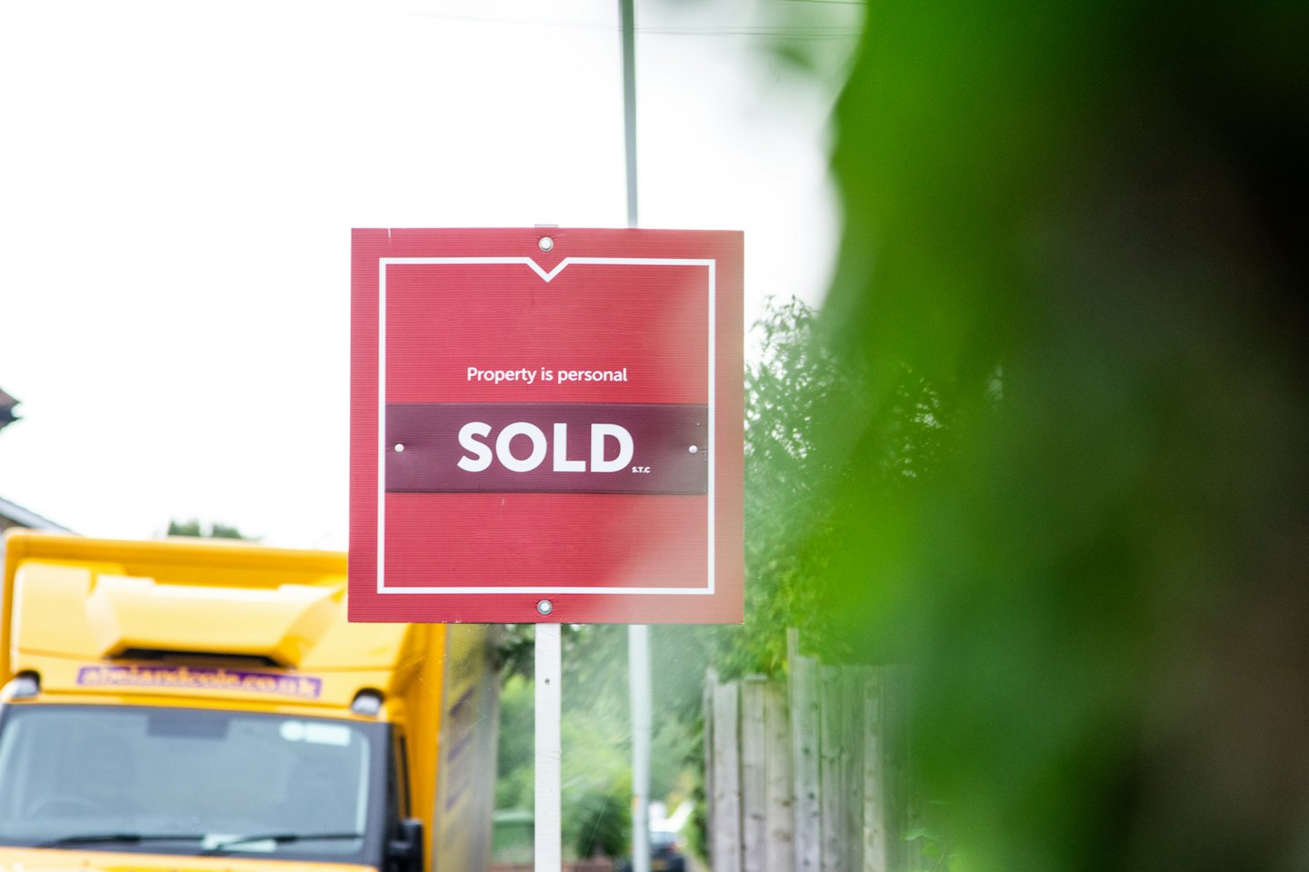A red sold sign stands in a residential yard.